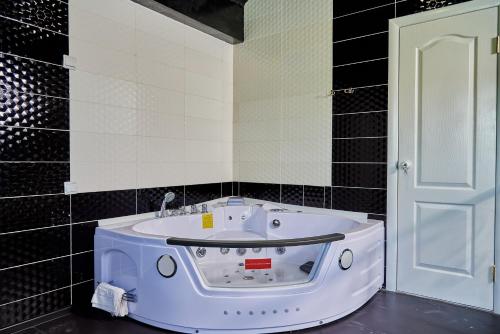 baño con lavabo blanco en una pared de azulejos negros en Hotel Lux Aquapark, en Poltava