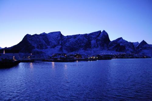 a large body of water with a mountain in the background at Toppøy Rorbuer in Reine