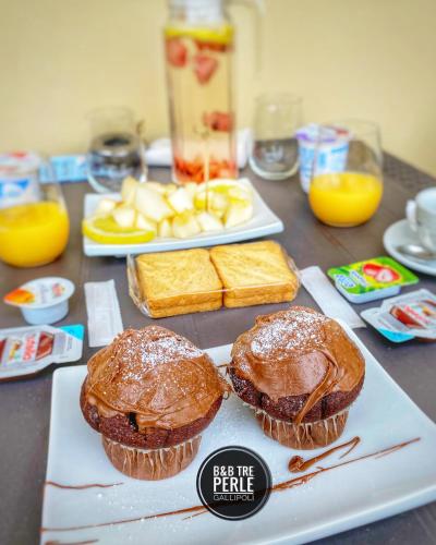 Zwei Muffins und Brot mit Orangensaft auf einem Tisch. in der Unterkunft B&b Tre Perle in Gallipoli