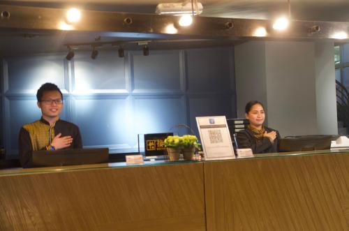 a couple of people sitting at a reception desk at G5 HOTEL AND SERVICED APARTMENT in Johor Bahru