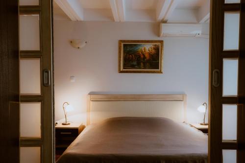a bedroom with a bed and a painting on the wall at Medical and Spa Centre Merkur in Vrnjačka Banja