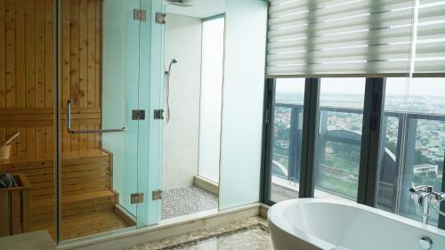 a bathroom with a tub and a shower with windows at The Mira Central Park Hotel in Bien Hoa