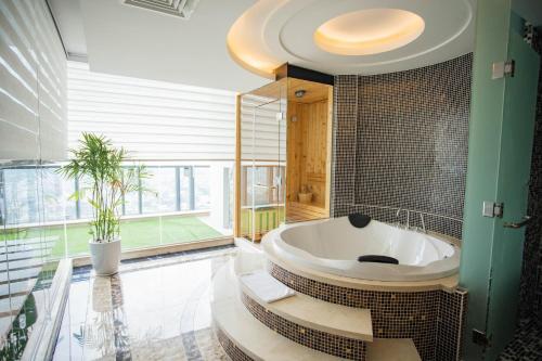 uma casa de banho com banheira e uma grande janela em The Mira Central Park Hotel em Bien Hoa