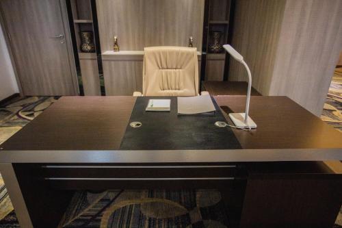 a desk with a lamp and a chair in a room at The Mira Central Park Hotel in Bien Hoa