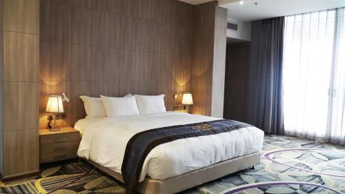 a bedroom with a large bed and a large window at The Mira Central Park Hotel in Bien Hoa