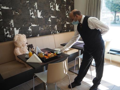 a man with a face mask and a table with a teddy bear at relexa hotel München in Munich