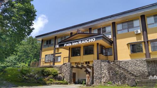 a yellow building with a sign that reads pas inn akko at Pals Inn Raicho in Hakuba
