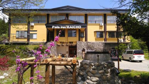 a yellow building with a sign that reads pas inn akka at Pals Inn Raicho in Hakuba