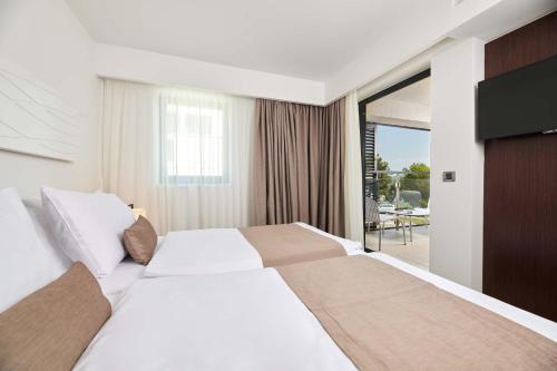 a hotel room with a large bed and a television at Hotel Parentium Plava Laguna in Poreč
