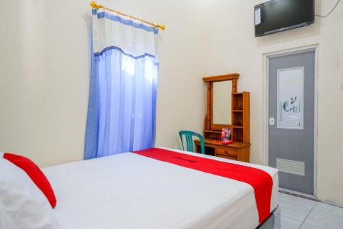 a bedroom with a white bed and a blue curtain at RedDoorz @ Jalan Raya Kaliwungu Selatan Kendal in Kendal