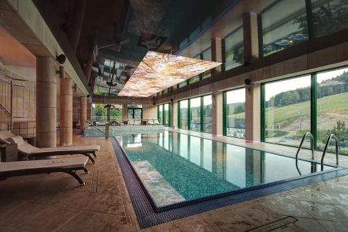 a large swimming pool in a building with windows at Hotel Pegaz in Krynica Zdrój