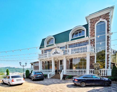 a large house with cars parked in front of it at Rosa Del Viento Hotel in Tuapse