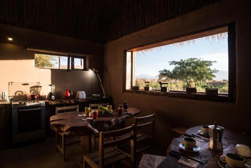 a kitchen with two tables and a window at Planeta Atacama Lodge in San Pedro de Atacama
