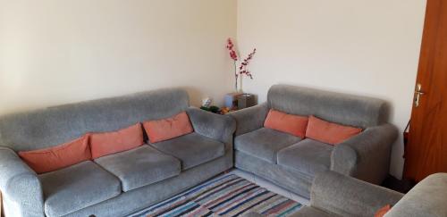 een woonkamer met twee grijze banken met oranje kussens bij Sunny apartment in quiet part of centre in Sarandë