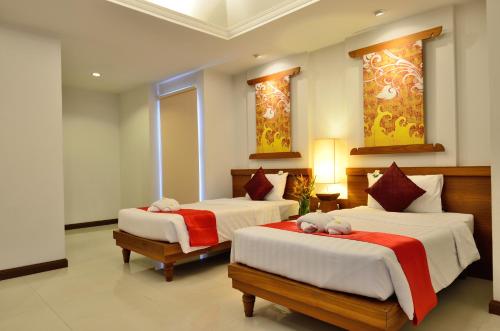 a bedroom with two beds with red and white sheets at First Bungalow Beach Resort in Chaweng