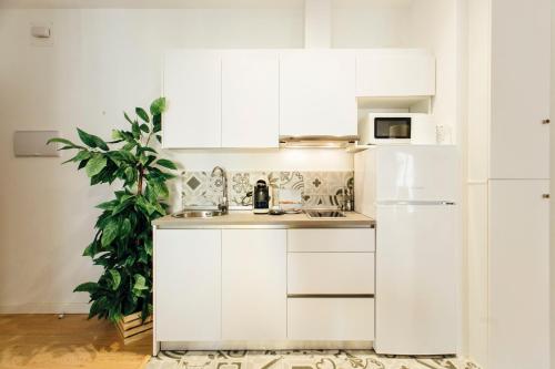 La cuisine est équipée de placards blancs et d'un réfrigérateur blanc. dans l'établissement Bright and comfortable- 2D 2B- Conde de Torrejón, à Séville