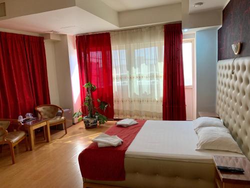 a bedroom with a bed and a window with red curtains at Hotel Funnytime in Bucharest