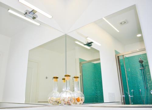 a bathroom mirror with four glass bottles on a shelf at Trastevere Boulevard in Rome