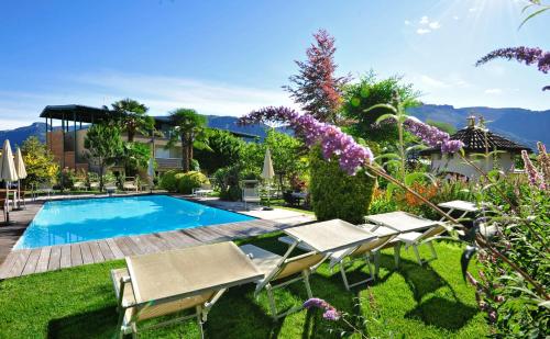 a swimming pool in a yard with chairs and flowers at Apparthotel Gartenresidence Nalserhof in Nalles