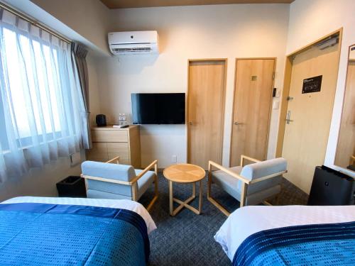 a hotel room with two beds and a table and chairs at Rinn Niomon in Kyoto