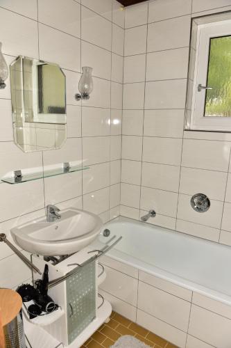 een witte badkamer met een wastafel en een bad bij Ferienwohnung Isabell in Ebensee