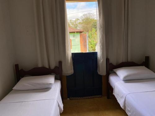zwei Betten in einem Zimmer mit Fenster in der Unterkunft Casa de hospedagem Mimos de Minas 2 in Tiradentes