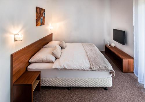 a bedroom with a bed with a wooden headboard at apartmán Ela - TATRY GOLF in Veľká Lomnica