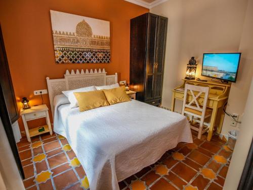 a bedroom with a white bed and a television at La Esperanza in Alcalá del Valle