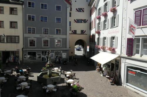 an empty courtyard with tables and chairs and buildings at Hotel Franziskaner in Chur