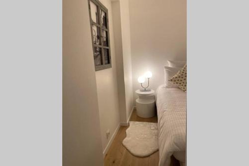 Dormitorio pequeño con cama y lámpara en la pared en Stylist and cosy appartement in Montparnasse, en París