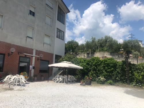 a group of chairs and an umbrella next to a building at Albergo Ristorante La Greppia in Montedivalli Chiesa