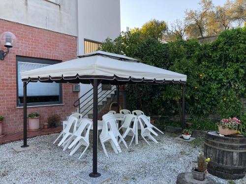 a group of white chairs under an umbrella at Albergo Ristorante La Greppia in Montedivalli Chiesa