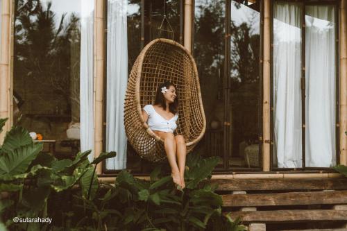 a woman sitting in a wicker chair on the porch of a house at Hideout Falcon in Selat