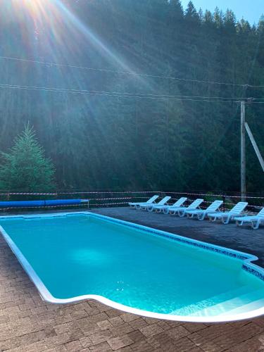 a swimming pool with lounge chairs next to a mountain at Forest House in Tatariv