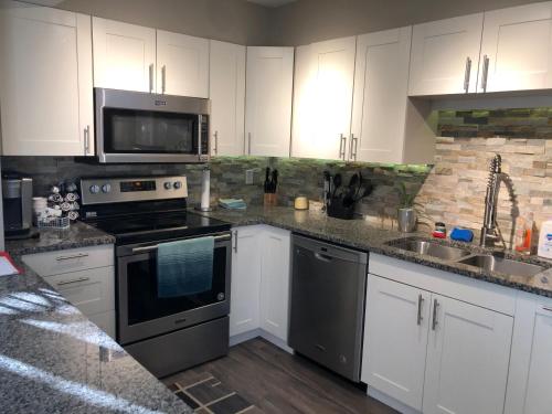 una cucina con elettrodomestici in acciaio inossidabile e armadietti bianchi di Tiki Beach Condo 1 a Campbellsport