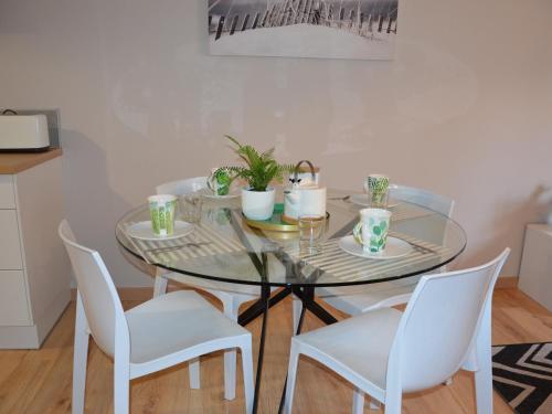 ヴァンヌにあるCharmant T2 Port de Vannesのダイニングルームテーブル(白い椅子、ガラスのテーブル付)
