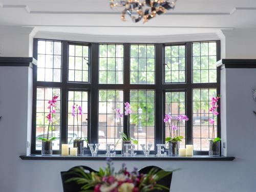 a window with vases and candles on a table with flowers at Verve Hotel in Bedford