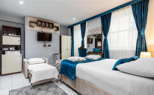 sypialnia z 2 łóżkami z niebieskimi zasłonami i telewizorem w obiekcie Vilenza Hotel w Londynie