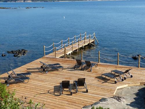 a wooden deck with chairs and a dock in the water at Résidence U Paviddonu in Porto-Vecchio