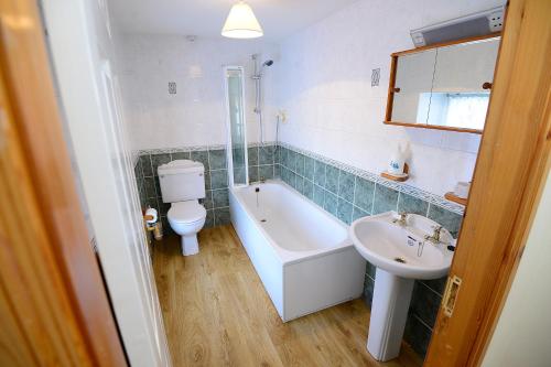 a bathroom with a tub and a toilet and a sink at Village Cottage Bushmills in Bushmills