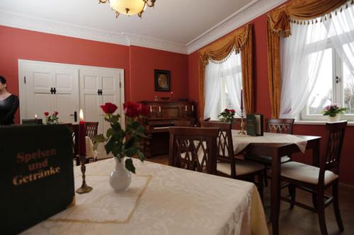 a dining room with red walls and a table with a vase of flowers at Villa Hierschel Droyßig in Droyßig