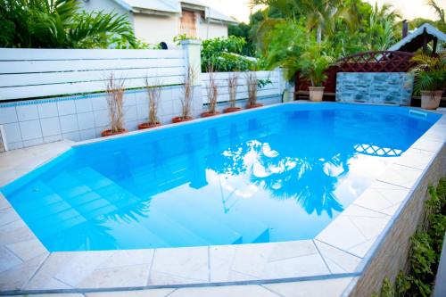a swimming pool with blue water and plants in a backyard at Villas Ixora in Sainte-Anne