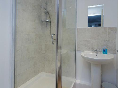 a shower with a glass door next to a sink at Vine Studio in Leeds