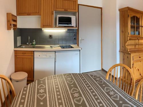 une petite cuisine avec une table et un micro-ondes dans l'établissement VAUJANYLOCATIONS - Cochette II Apt 12, à Vaujany
