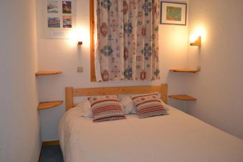 una camera con un letto con due cuscini sopra di VAUJANYLOCATIONS - La Fare Apt 10 a Vaujany