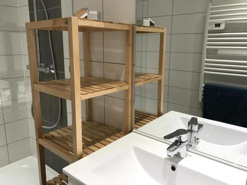 La salle de bains est pourvue d'un lavabo et d'une étagère au-dessus d'un lavabo. dans l'établissement VAUJANYLOCATIONS - La Fare Apt 12, à Vaujany