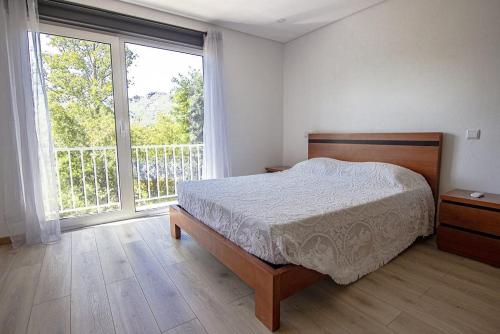 um quarto com uma cama e uma grande janela em Sousa Horizonte - Louredo em Vieira do Minho