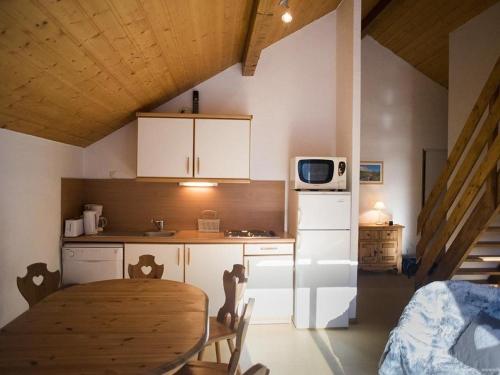 une petite cuisine avec une table et un micro-ondes dans l'établissement VAUJANYLOCATIONS - Chalet De Marie, à Vaujany