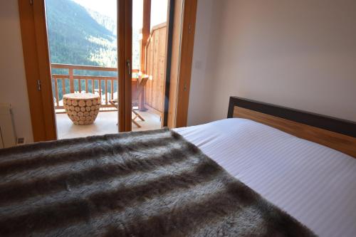 - une chambre avec un lit et un balcon dans l'établissement VAUJANYLOCATIONS - Domaine du Pâtre, à Vaujany