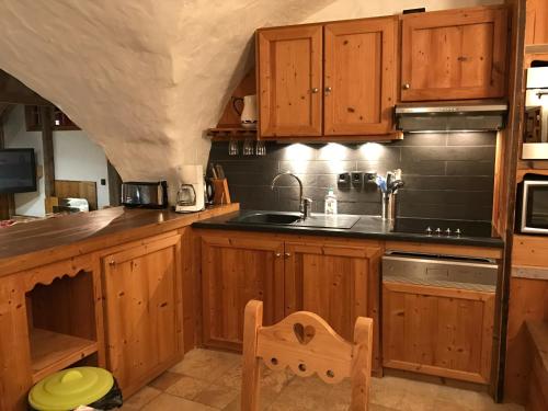 une cuisine avec des armoires en bois et un évier dans l'établissement VAUJANYLOCATIONS - Le Grenier de Germaine, à Vaujany